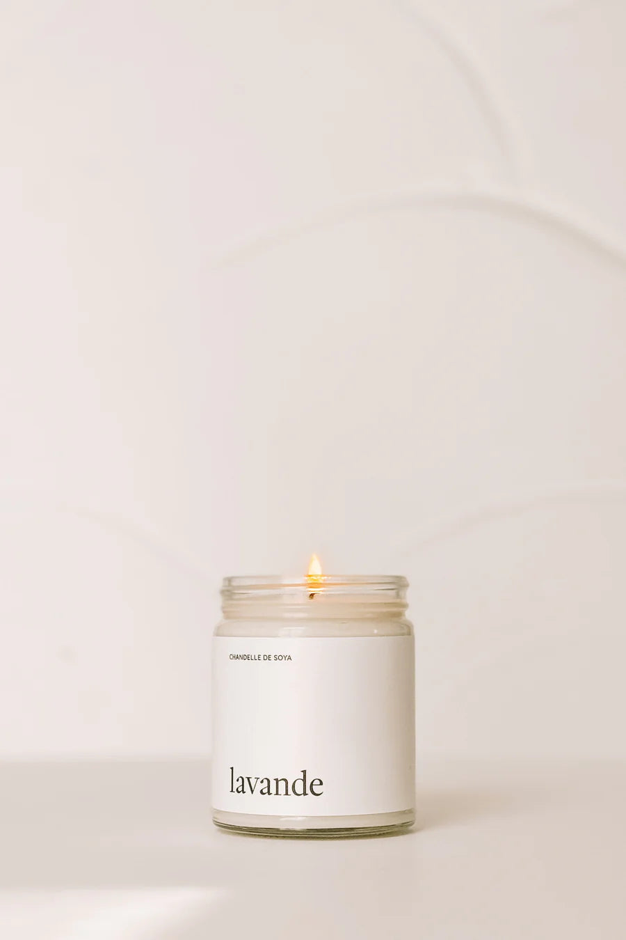 Chandelle de soya parfumée à la lavande posée sur une table blanche dans un style minimaliste.