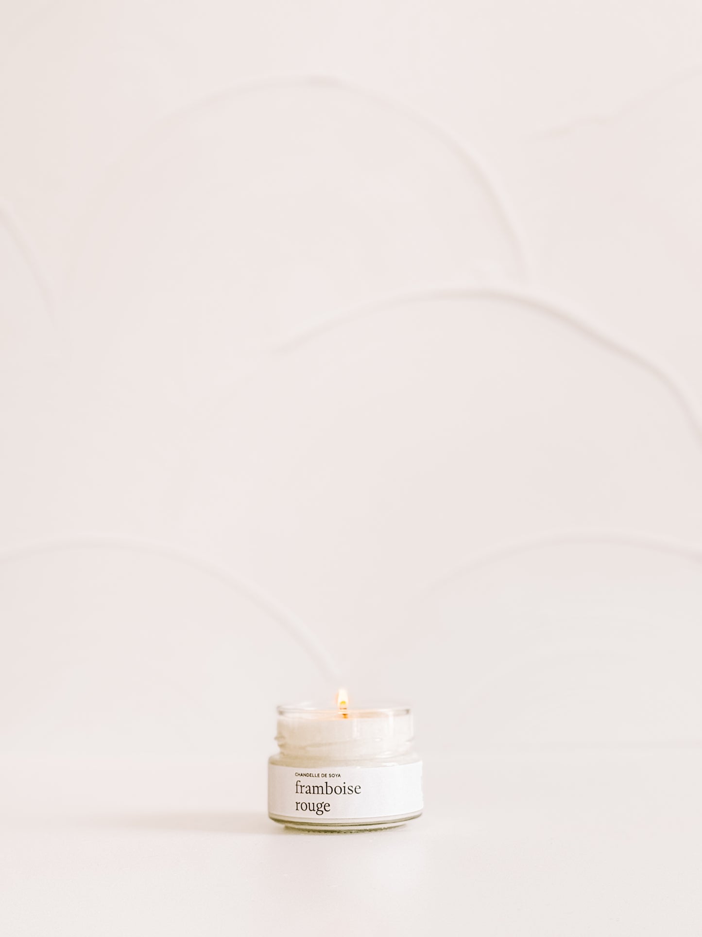 Chandelle de soya framboise rouge format mini, diffusant une lumière chaleureuse.