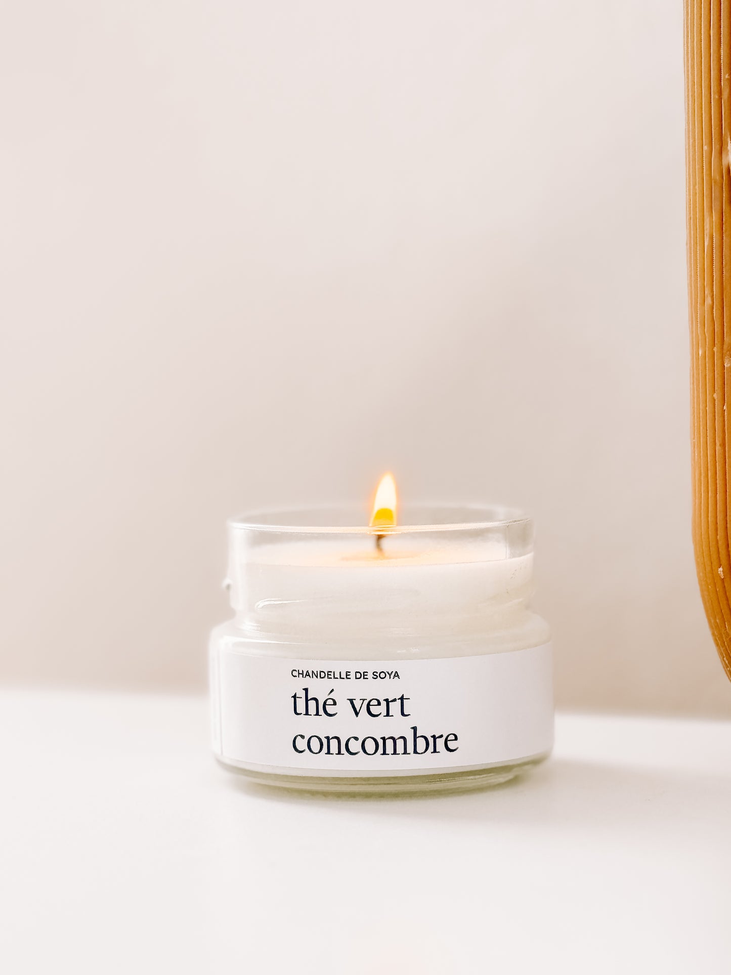 Une chandelle de soya the vert concombre en format compact, 106ml, illuminee et mise en scene sur une etagere blanche.