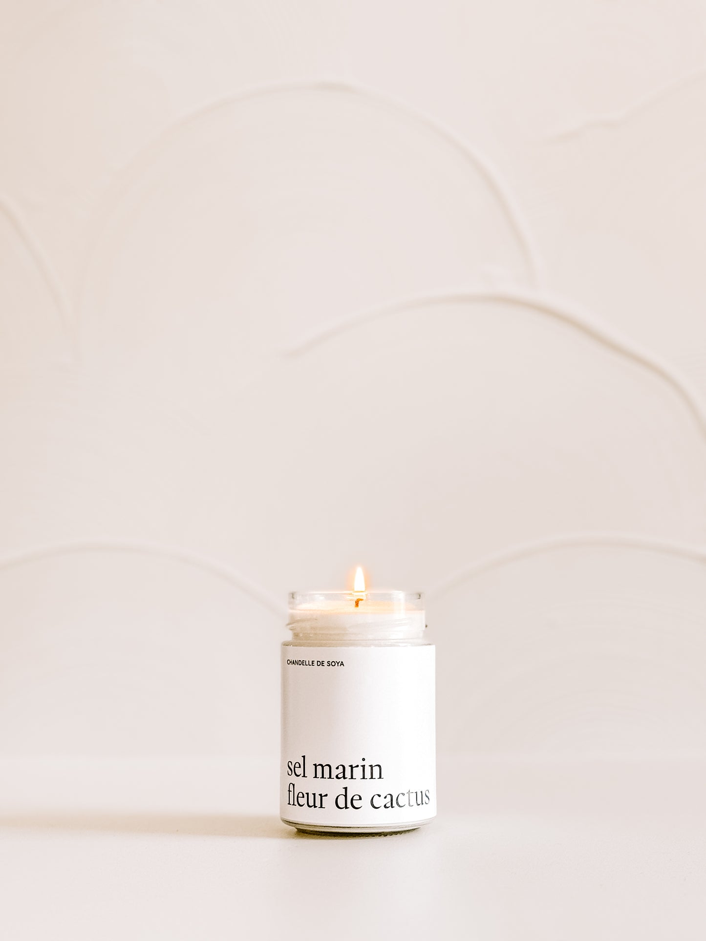 Chandelle allumée Sel marin fleur de cactus, mise en avant avec un fond minimaliste en teintes crème.