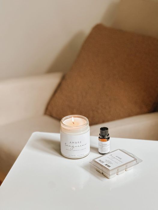 Chandelle de soya bio Ambre et tangerine par Marée, posée sur une table, accompagnée d’une huile essentielle et d’un cube de cire parfumée.
