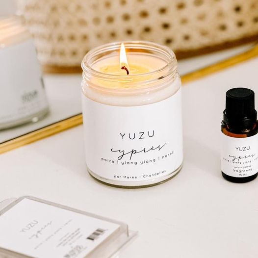 Chandelle Yuzu cypres allumée, posée près d'un miroir et de produits assortis, apportant une touche d'élégance.