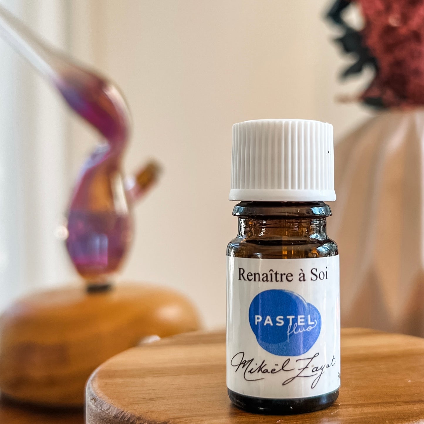Flacon d'huile essentielle Renaître a Soi de Mikael Zayat posé sur une surface en bois, symbole de recentrage et de retour à l'essentiel pour un bien-être profond.