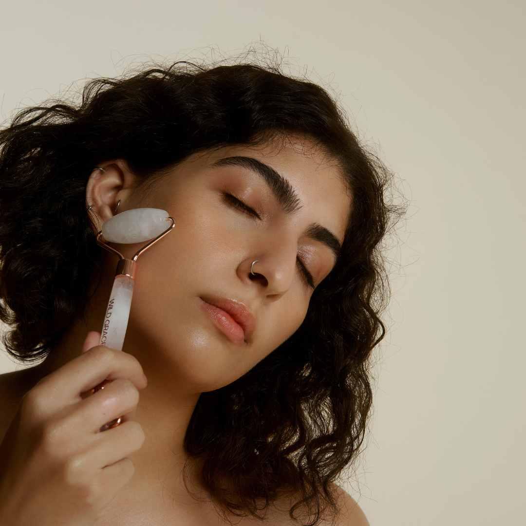 Application d’un rouleau de quartz blanc sur le visage pour stimuler la circulation et lisser les traits, dans une routine beauté naturelle et apaisante.