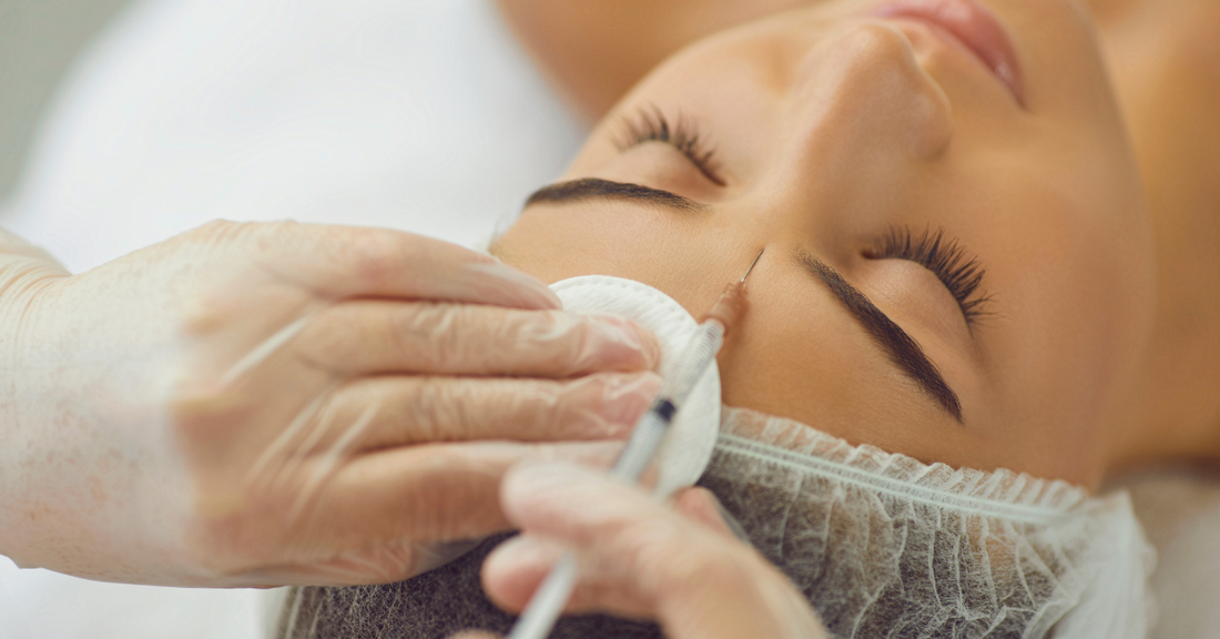 Jeune femme recevant une injection entre les sourcils, mettant en avant l'importance de différer l'utilisation des injectables avant 35 ans pour préserver l'harmonie naturelle du visage.