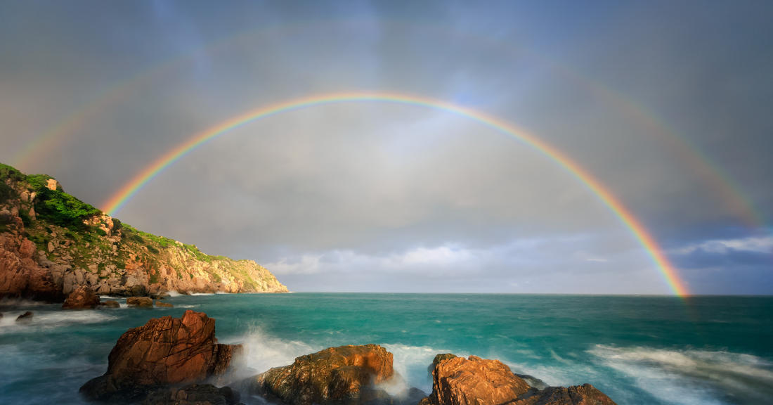 Un double arc-en-ciel au-dessus de l’océan, symbolisant la barrière hydrolipidique qui protège la peau des agressions extérieures et préserve son équilibre.