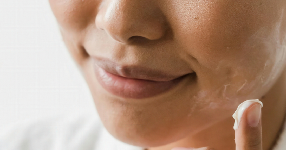 Gros plan sur une femme appliquant une crème hydratante sur son visage, illustrant l’importance d’une routine de soin bien adaptée.