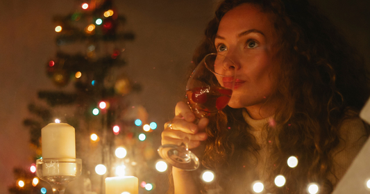 Femme buvant un verre durant la période de Noël, reflétant bien-être et bonheur, avec un teint et un maquillage bien présenté.