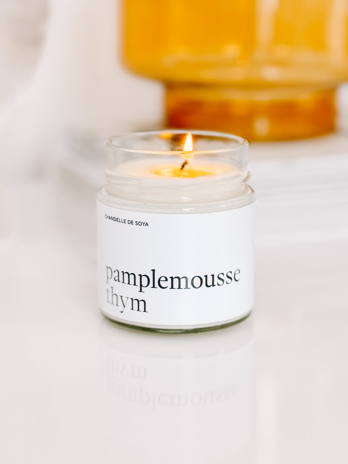 Chandelle de soya Pamplemousse Thym allumée, diffusant une lumière douce pour une ambiance apaisante.