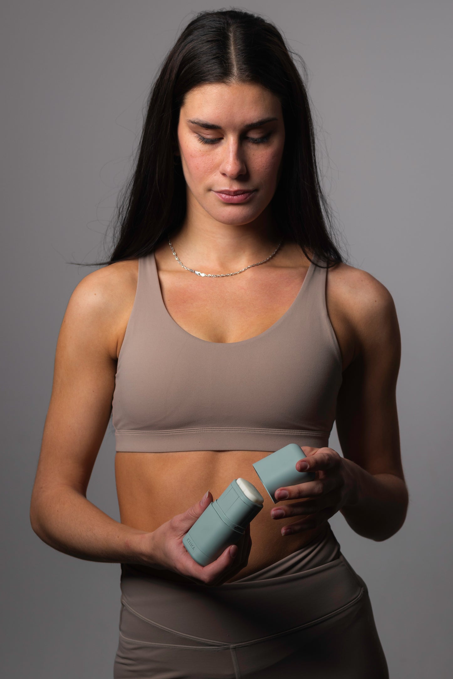 Femme tenant un applicateur de déodorant rechargeable KIIMA, illustrant une routine de soins corporels naturels adaptée à un mode de vie actif.