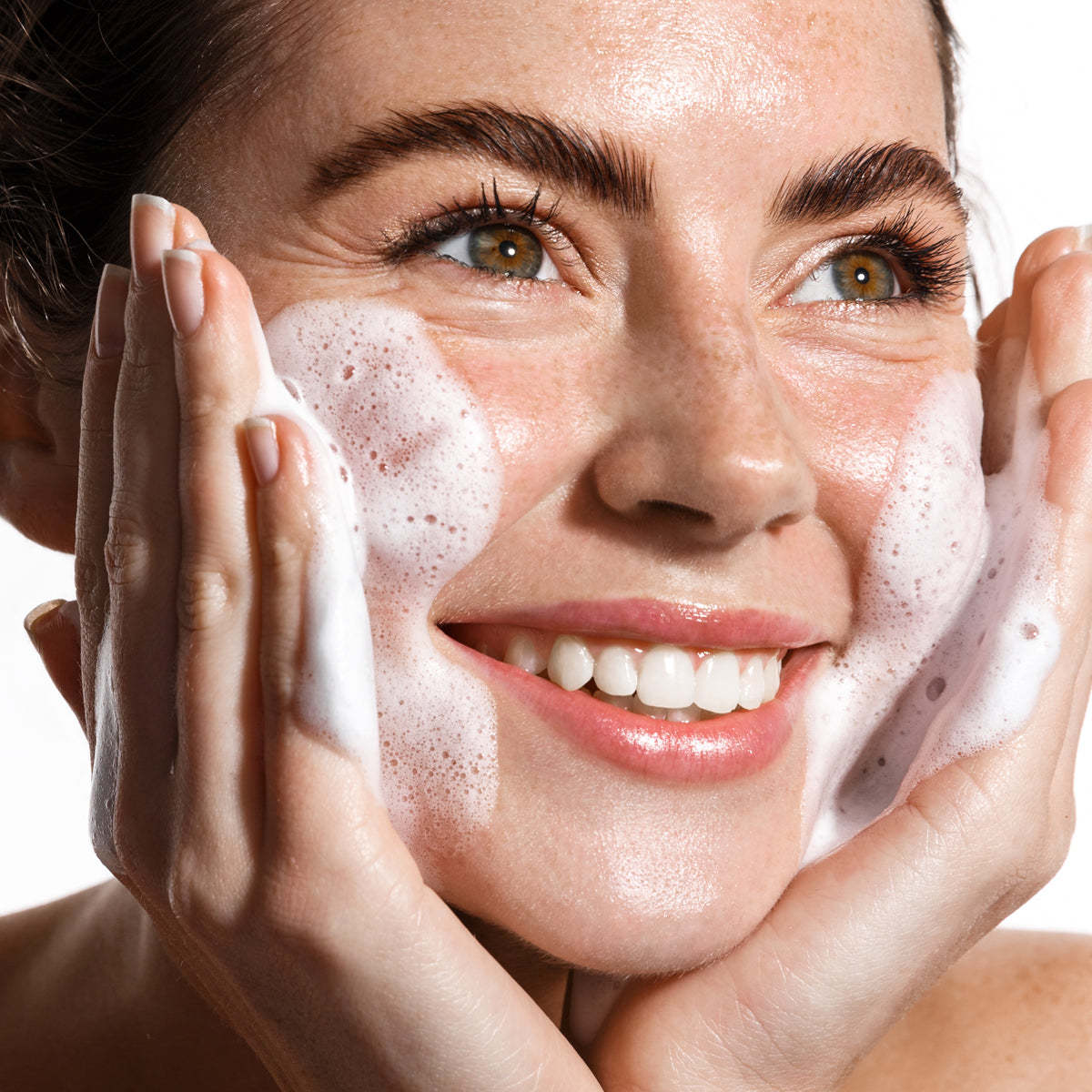 Femme souriante appliquant la mousse micellaire Bioacne sur son visage, illustrant un nettoyage doux et efficace pour une peau fraiche et purifiee.