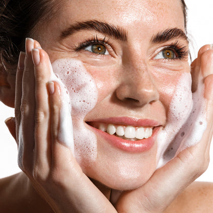 Femme souriante appliquant la mousse micellaire Bioacne sur son visage, illustrant un nettoyage doux et efficace pour une peau fraiche et purifiee.