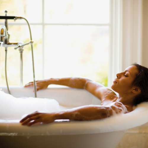 Une femme profite d’un bain moussant relaxant, immergée dans une baignoire remplie de mousse. Un instant de bien-être inspiré du Rituel Boréal de Selv Rituel, conçu pour vivifier et revitaliser le corps et l'esprit.