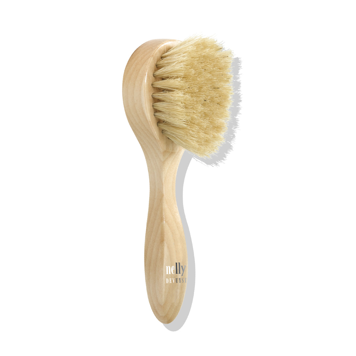 Brosse exfoliante visage en bois Nelly DeVuyst avec poils naturels, conçue pour stimuler la circulation et affiner le grain de peau tout en douceur.