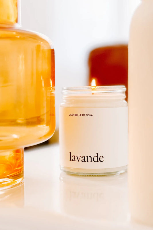 Chandelle de soya lavande entourée de décorations chaleureuses et d'une ambiance lumineuse.