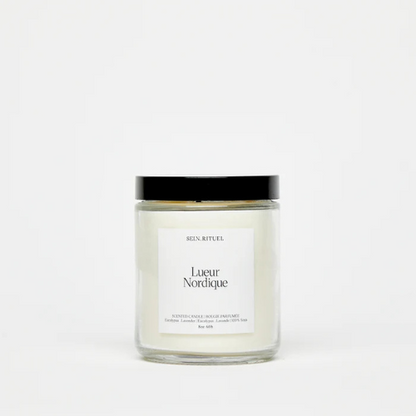 Chandelle en pot de verre avec couvercle noir et étiquette minimaliste blanche, offrant une esthétique épurée et naturelle.