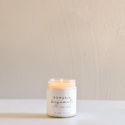 Chandelle Romarin Bergamote allumée sur une table épurée, idéale pour créer une atmosphère chaleureuse et naturelle.