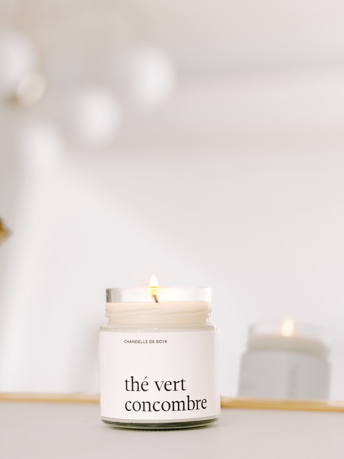 Une chandelle de soya the vert concombre illuminee, refletee dans un miroir pour une ambiance lumineuse.