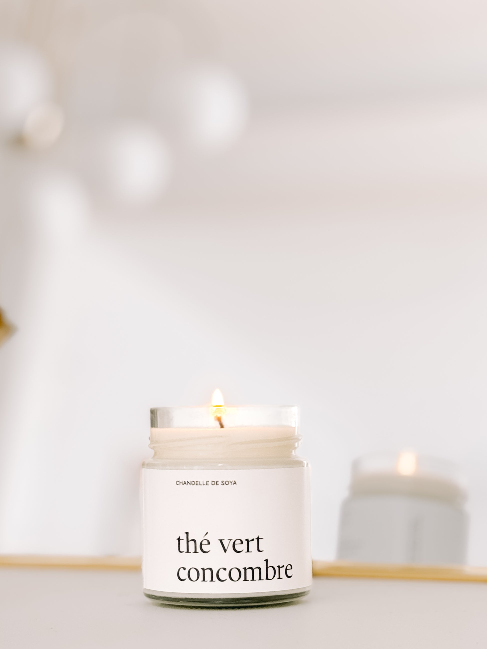 Une chandelle de soya the vert concombre illuminee, refletee dans un miroir pour une ambiance lumineuse.