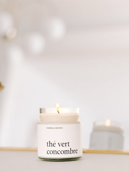 Une chandelle de soya the vert concombre illuminee, refletee dans un miroir pour une ambiance lumineuse.