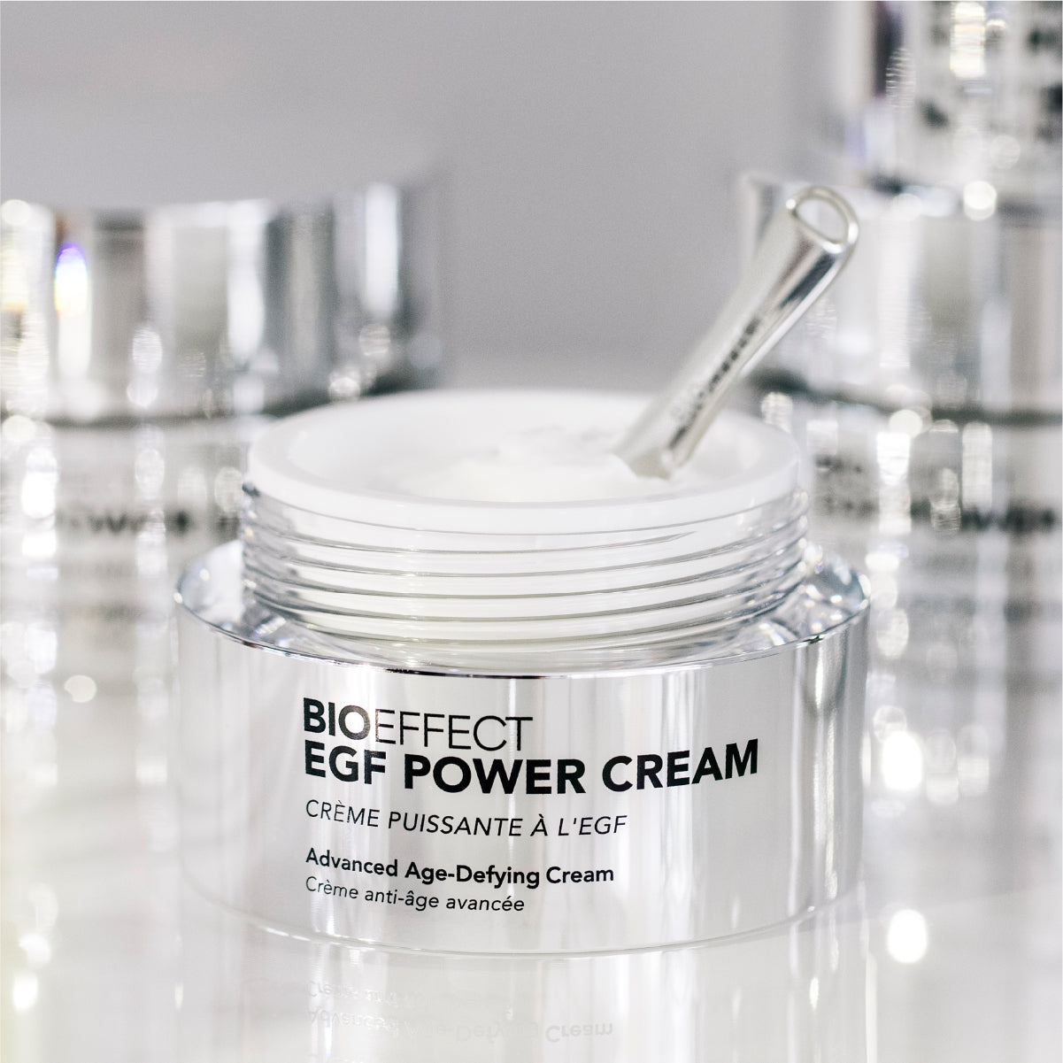Pot de la EGF Power Cream avec sa spatule posée dans la crème, dans une ambiance éclatante et haut de gamme, refletant le soin anti-âge avancé.