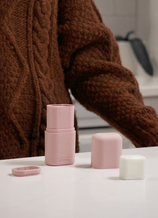 Application d’un déodorant rechargeable Kiima rose posé sur un comptoir, illustrant un rituel de soin naturel, minimaliste et écoresponsable.
