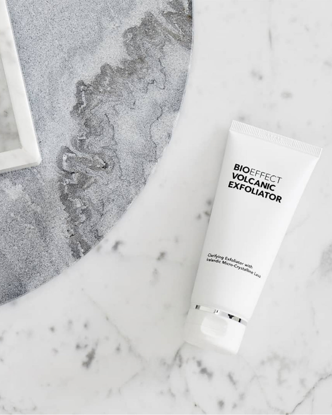 Le Volcanic Exfoliator de Bioeffect repose sur une surface de marbre blanc et de pierre grise, symbolisant purete, clarte et soin raffine de la peau.
