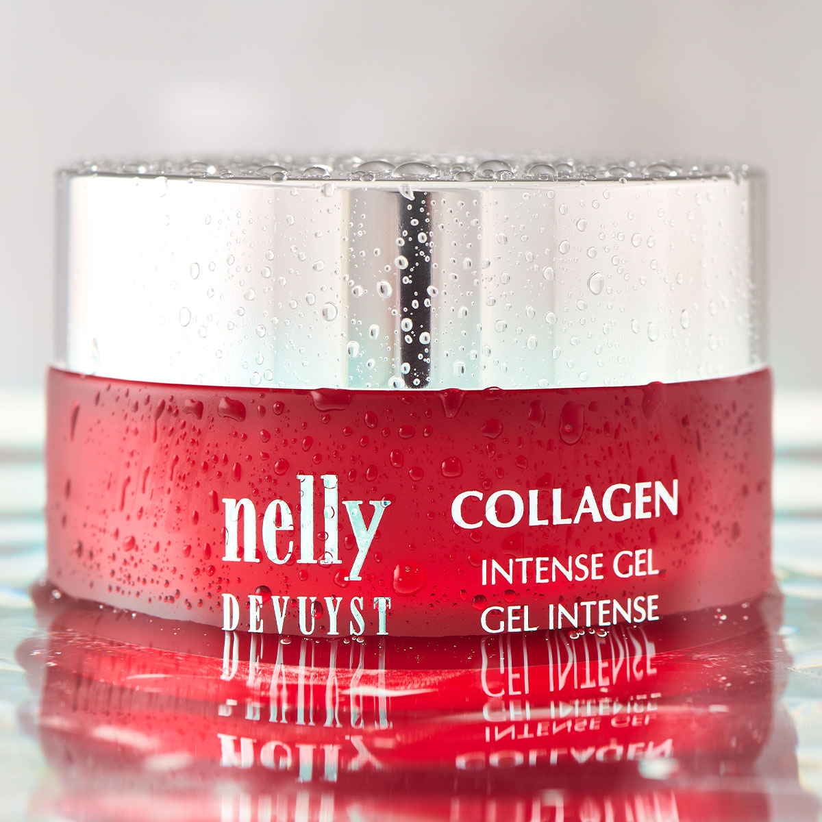 Pot rouge du Gel Intense Collagène Nelly DeVuyst couvert de fines gouttes d’eau, symbole d’hydratation profonde et de fermeté cutanée.