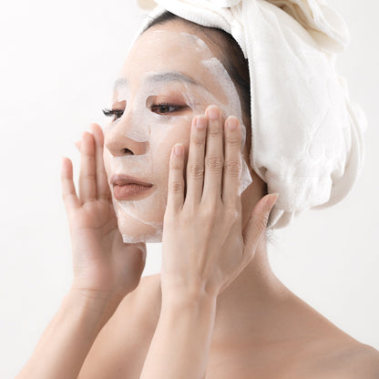 Femme appliquant le Masque Lifting Complex Nelly DeVuyst, un soin facial en feuille hydratant et raffermissant qui lifte la peau et redonne éclat et élasticité au visage.