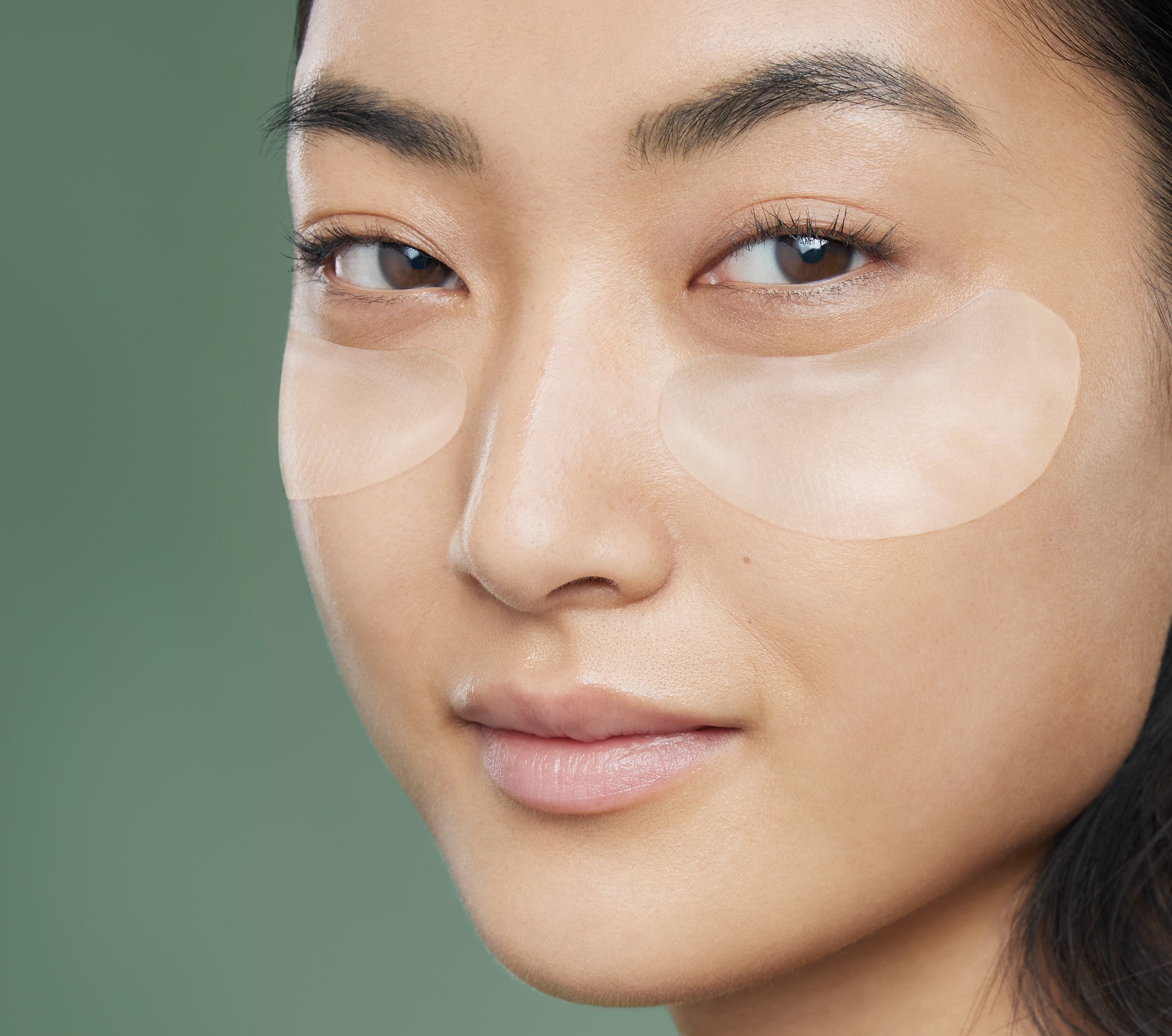 Patchs hydrogel Bioeffect appliqués sous les yeux d'une femme asiatique au teint naturel et lumineux, pour lisser, hydrater et rafraîchir le contour de l'œil.