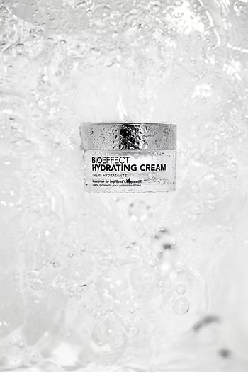 Pot de crème Bioeffect Hydrating Cream entouré d’eau et de reflets lumineux, soulignant son pouvoir hydratant et sa fraîcheur éclatante.