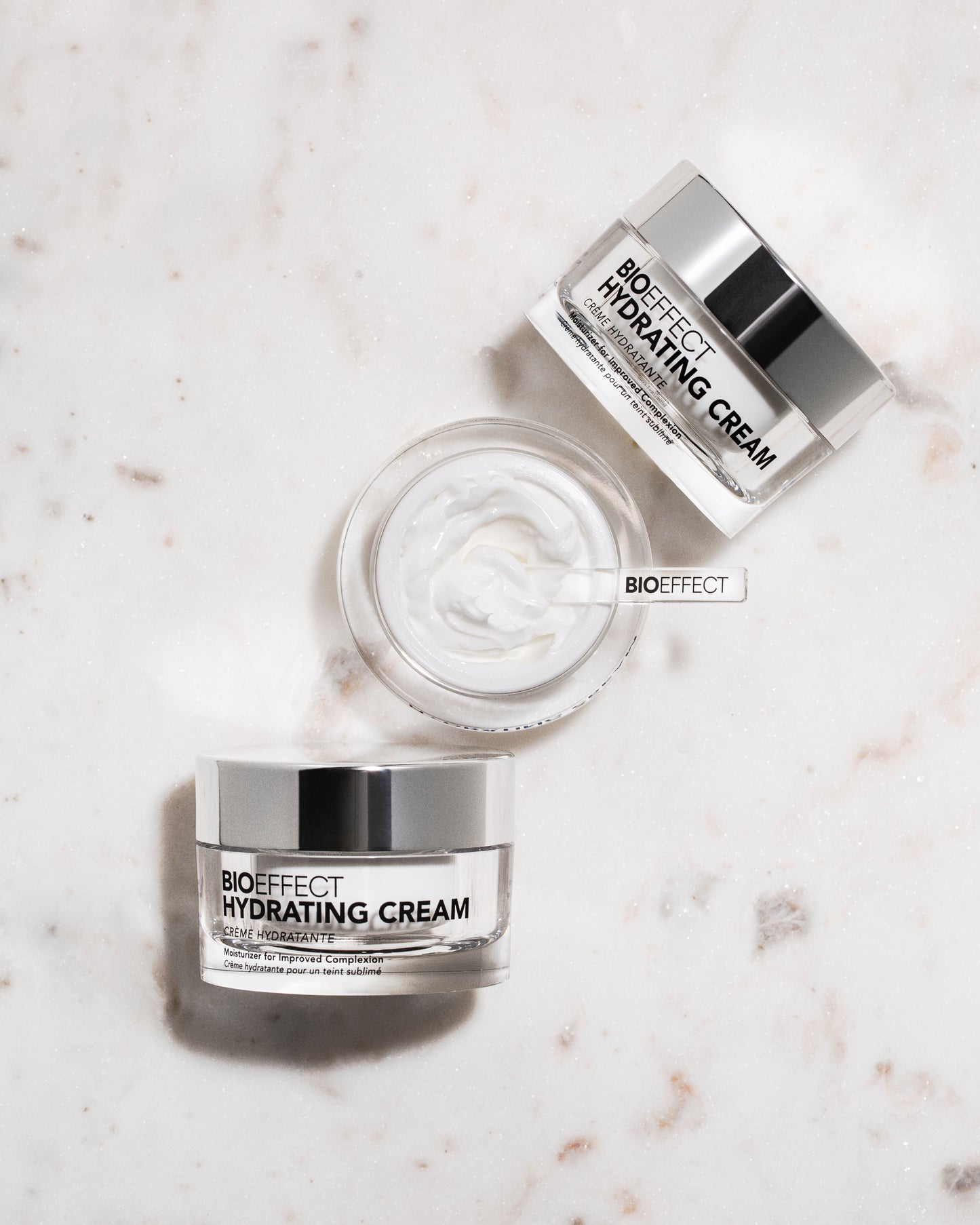 Trois pots de la crème Bioeffect disposés sur une surface en marbre clair, avec vue du dessus sur la texture, renforçant l’élégance et le soin de qualité.