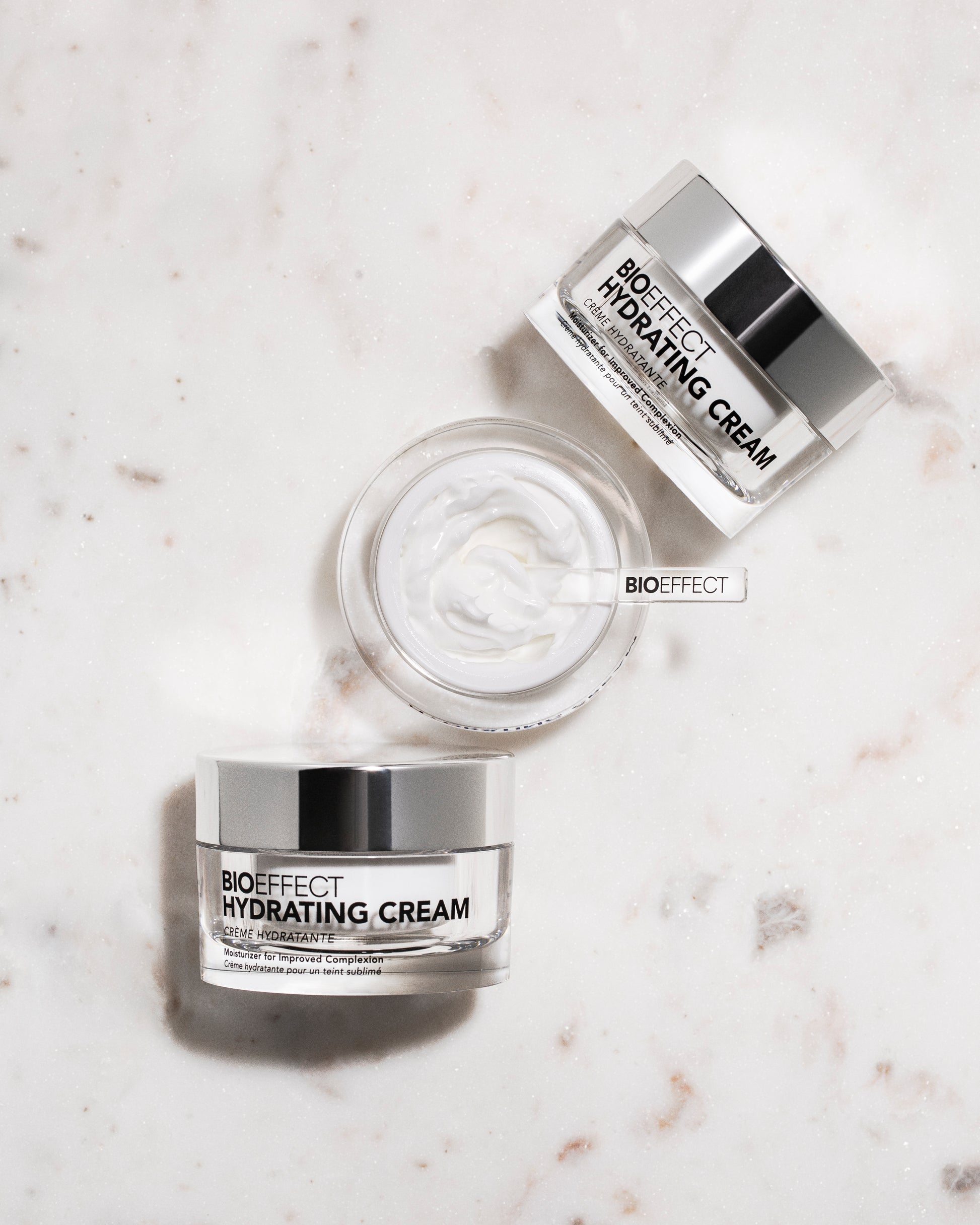 Trois pots de la crème Bioeffect disposés sur une surface en marbre clair, avec vue du dessus sur la texture, renforçant l’élégance et le soin de qualité.