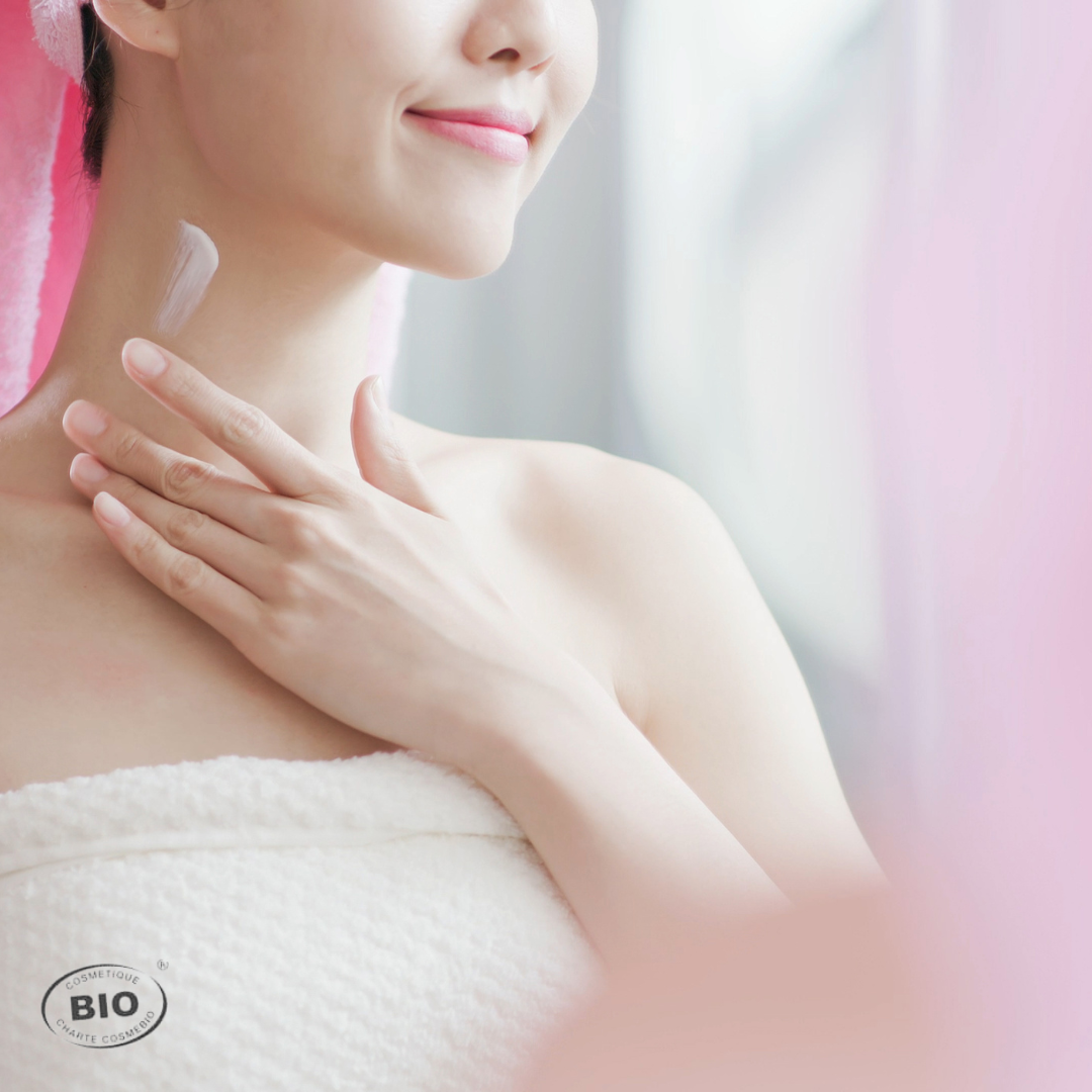 Femme souriante appliquant une crème bio sur le cou pour raffermir et nourrir la peau, geste clé du rituel beauté du forfait Le Luxe.
